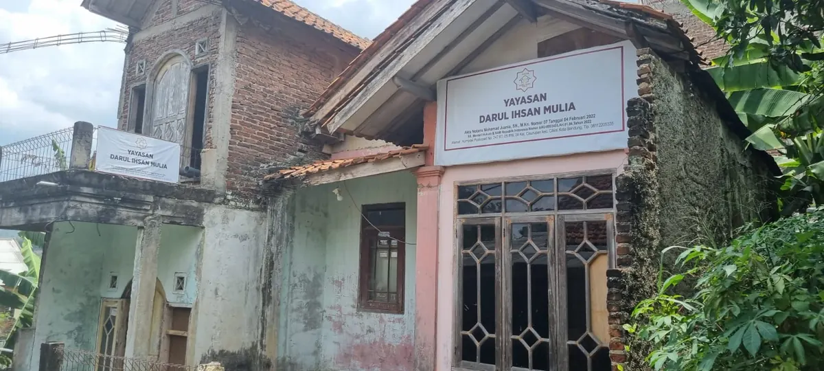 Bangunan lama di lokasi Rumah Tahfidz dengan papan nama dan cat yang sudah memudar